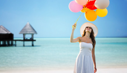 Image showing smiling young woman in sunglasses with balloons