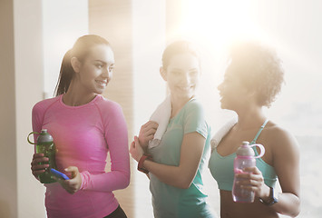 Image showing happy women with bottles of water in gym