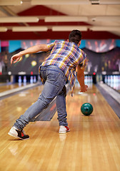 Image showing happy young man throwing ball in bowling club