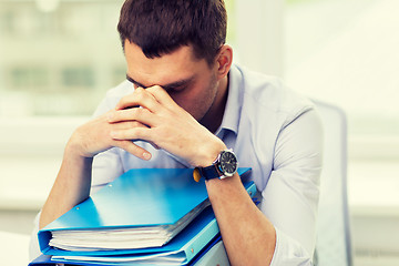 Image showing sad businessman with stack of folders at office