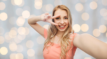 Image showing smiling woman taking selfie and showing peace sign