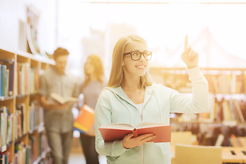 Image showing happy student girl or woman with book in library