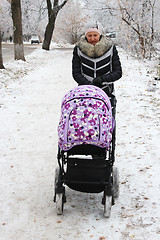 Image showing Woman with baby in perambulator walking in winter 