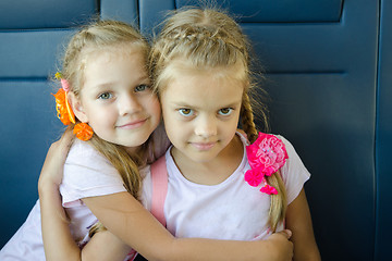 Image showing Two girls hugging look in the frame, sitting in an electric train, close-up