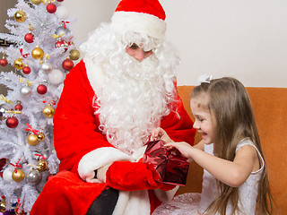 Image showing Little girl joyfully opens a gift that keeps grandfather frost