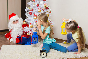 Image showing Two girls with flashlights to see Santa Claus who was trying to discreetly put the presents under the Christmas tree