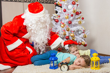 Image showing Santa Claus brought gifts and pats on the head of sleeping children