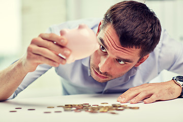 Image showing businessman with piggy bank and coins at office