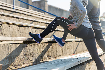 Image showing close up of couple stretching leg on stadium