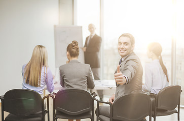 Image showing businessman with team showing thumbs up in office