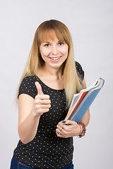 Image showing Young woman with folders in hands happily smiling and showing thumb