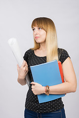 Image showing Young girl student with folders and a roll of paper in his hand sadly looks aside