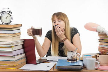 Image showing Girl student doing night yawns, holding another cup of coffee hands