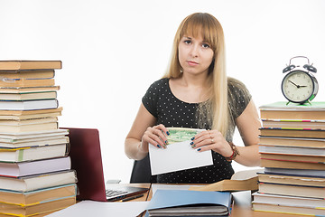 Image showing Upset girl student puts money in an envelope to bribe the teacher in the exam