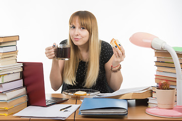 Image showing Young teacher drinks coffee with a sandwich in the workplace