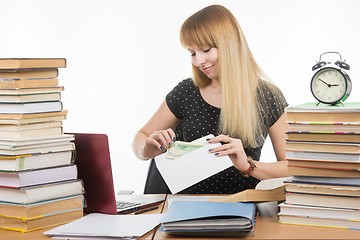 Image showing The girl puts money in an envelope to bribe the teacher in the exam