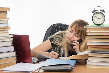 Image showing Student talking on the phone writing something on a piece of paper