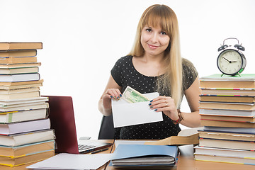 Image showing The girl puts money in an envelope to bribe the teacher in the exam, and looked into the frame