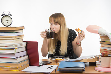 Image showing Young teacher drinks coffee with a sandwich in the workplace