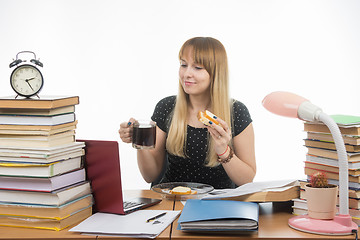 Image showing Sleepy student bites sandwich with coffee