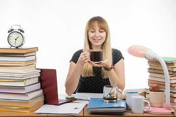 Image showing Girl student happily looks at a glass of coffee