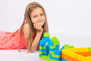 Image showing Seven-year girl builds a house from the block designer and thoughtful and fun looks in the frame