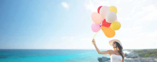 Image showing smiling young woman in sunglasses with balloons