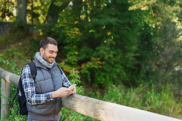 Image showing happy man with backpack and smartphone outdoors