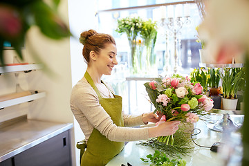 Image showing smiling florist woman making bunch at flower shop