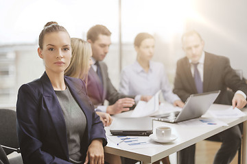 Image showing businesswoman in office with team on the back