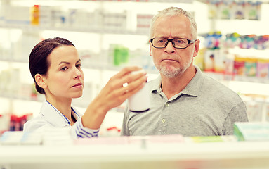 Image showing pharmacist showing drug to senior man at pharmacy