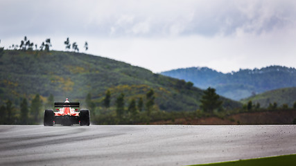 Image showing Racing car in landscape of hills with spray of rain