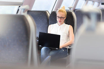 Image showing Woman travelling by train working on laptop.