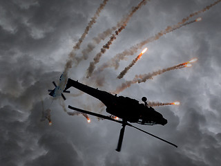 Image showing Silhouette of an attack helicopter firing flares