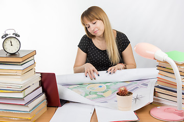 Image showing Girl design student sitting at a desk and is tired deploys a large drawing