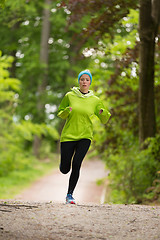 Image showing Sporty young female runner in the forest. 