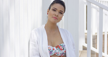 Image showing Smiling woman in swimsuit sitting near fence