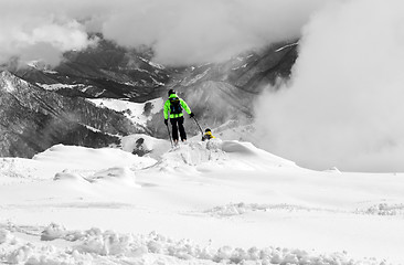 Image showing Freeriders on off-piste slope and mountains in mist. Selective c