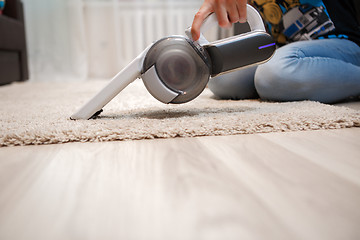 Image showing Cleaning of rug in house portable rechargeable vacuum cleaner