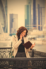 Image showing woman in a bright coat with notebook talking on mobile