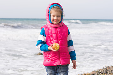 Image showing Portrait of a five year old girl with an apple on the beach