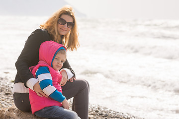 Image showing My mother and five year old daughter sit on the beach and looked at turning frame