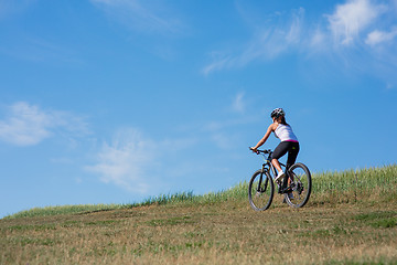 Image showing Sport bike woman on the meadow with a beautiful landscape