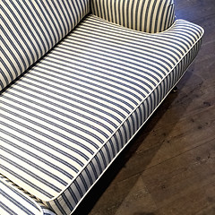 Image showing Elegant striped sofa on dark wooden floor