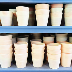 Image showing Simple clay pots on blue shelves