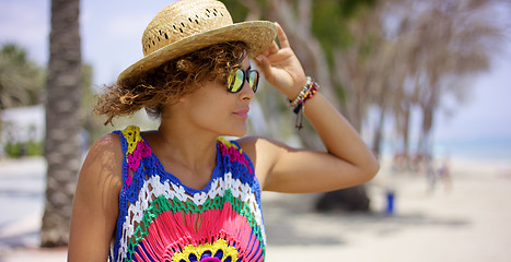 Image showing Pretty woman in sunglasses adjusting hat