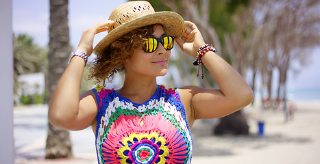 Image showing Pretty woman in sunglasses adjusting hat