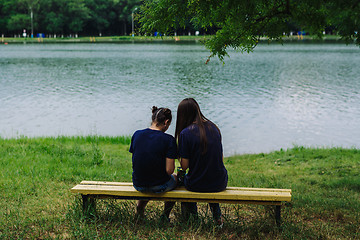 Image showing Women sit on a bench and take selfies