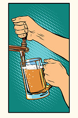 Image showing The bartender pours a glass of beer