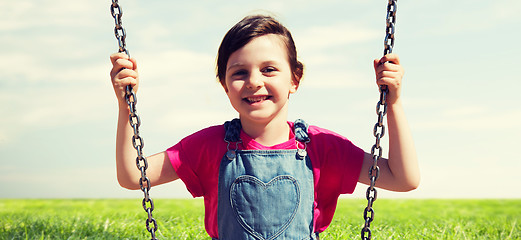 Image showing happy little girl swinging on swing outdoors